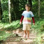 Chłopiec idzie leśną ścieżką w słoneczny dzień