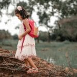 Dziewczynka z różowym plecakiem idzie leśną ścieżką