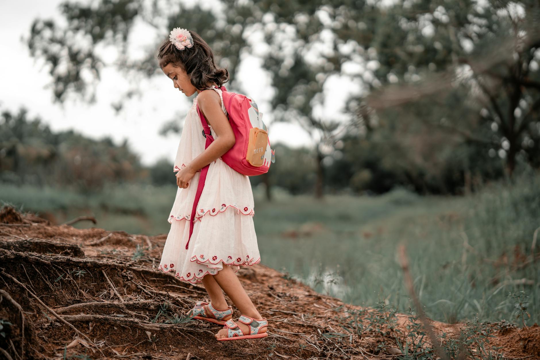 Dziewczynka z różowym plecakiem idzie leśną ścieżką