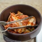 Miska tradycyjnego koreańskiego kimchi z metalowymi szczypcami