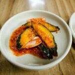 Pikantne koreańskie kimchi z ogórków w białej misce na drewnianym stole