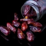 Suszone daktyle wysypujące się ze szklanego słoika na błyszczący blat