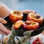 Kobieta przygotowuje pieczone jabłka nadziewane bakaliami na zimowy deser
