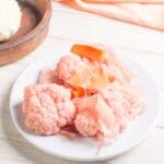 Różowy kalafior i marchewki z kiszonki na białym talerzu