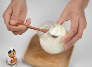 Probiotyk czy prebiotyk? Czym się różnią i kiedy brać każdy z nich Mężczyzna jedzący jogurt naturalny ze słoika bambusową łyżką